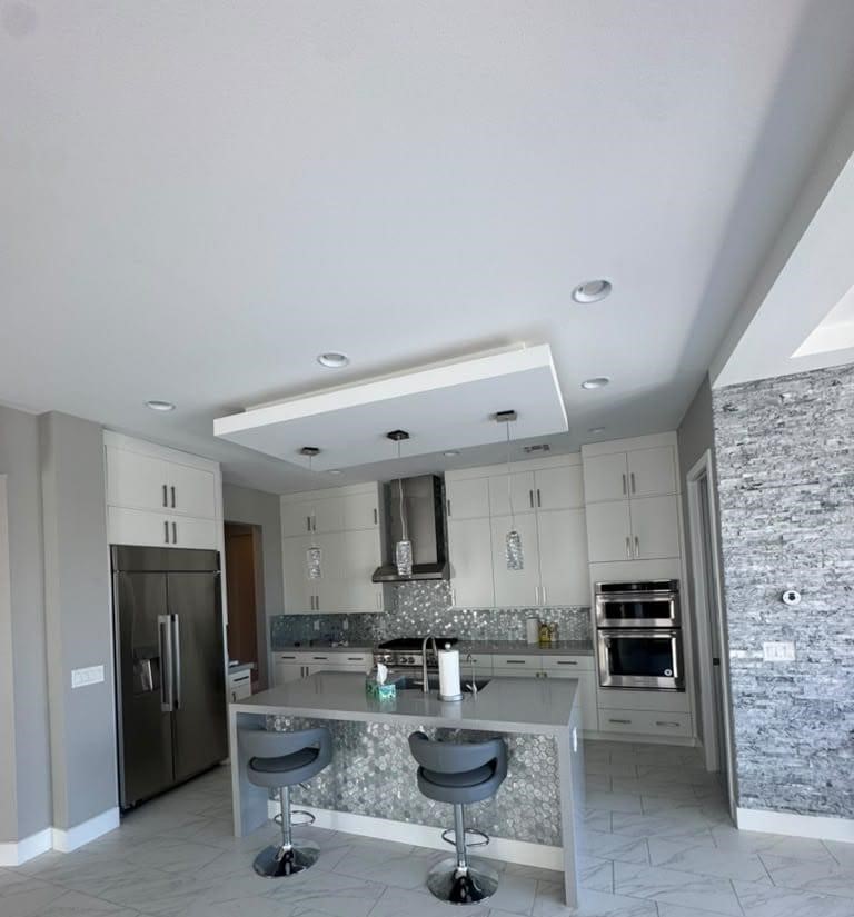 Modern gray and white kitchen with island, bar stools, and stone accent wall