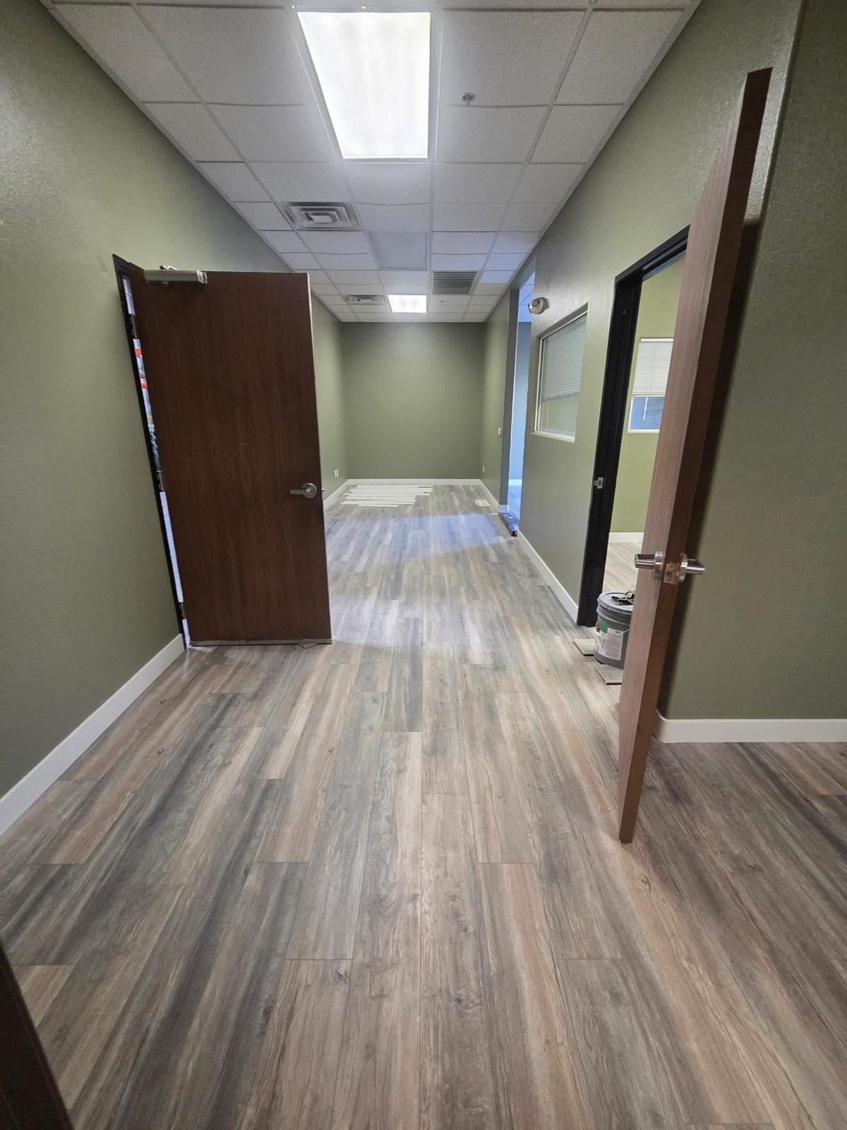 Office hallway with newly installed wood-look vinyl plank flooring and green walls